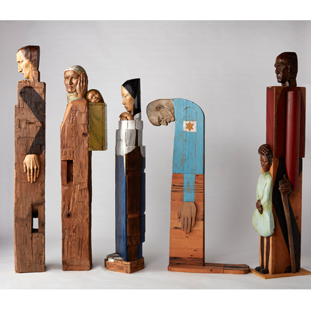 5 wooden sculptures of various people in a line