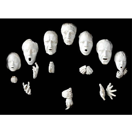 White Sculpture of 7 heads and 7 pairs of hands on a black background