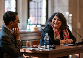 Sunil Amrith and Sharmila Sen sitting at a desk, engaged in conversation and smiling.